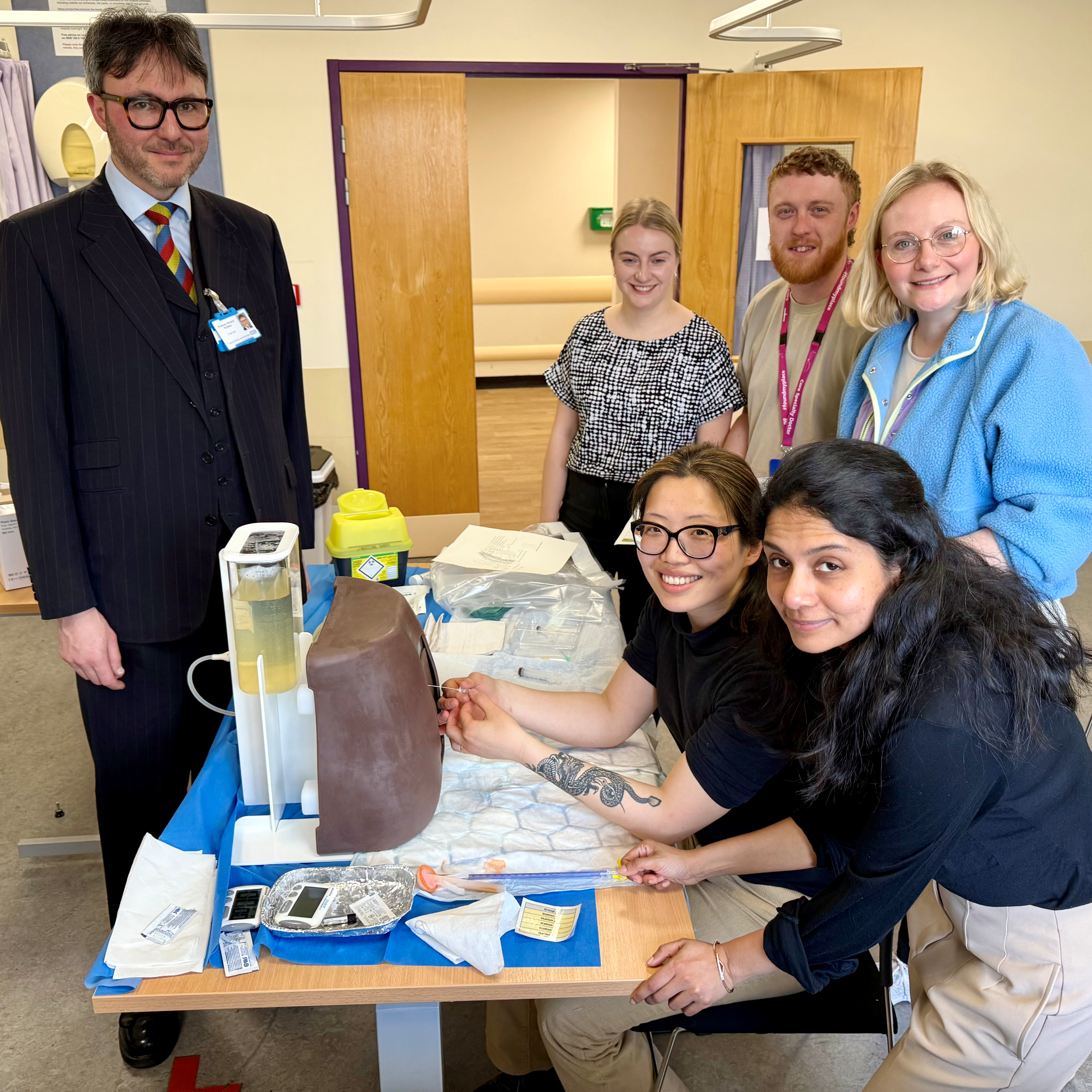 People smiling round a table with medical equipment on it