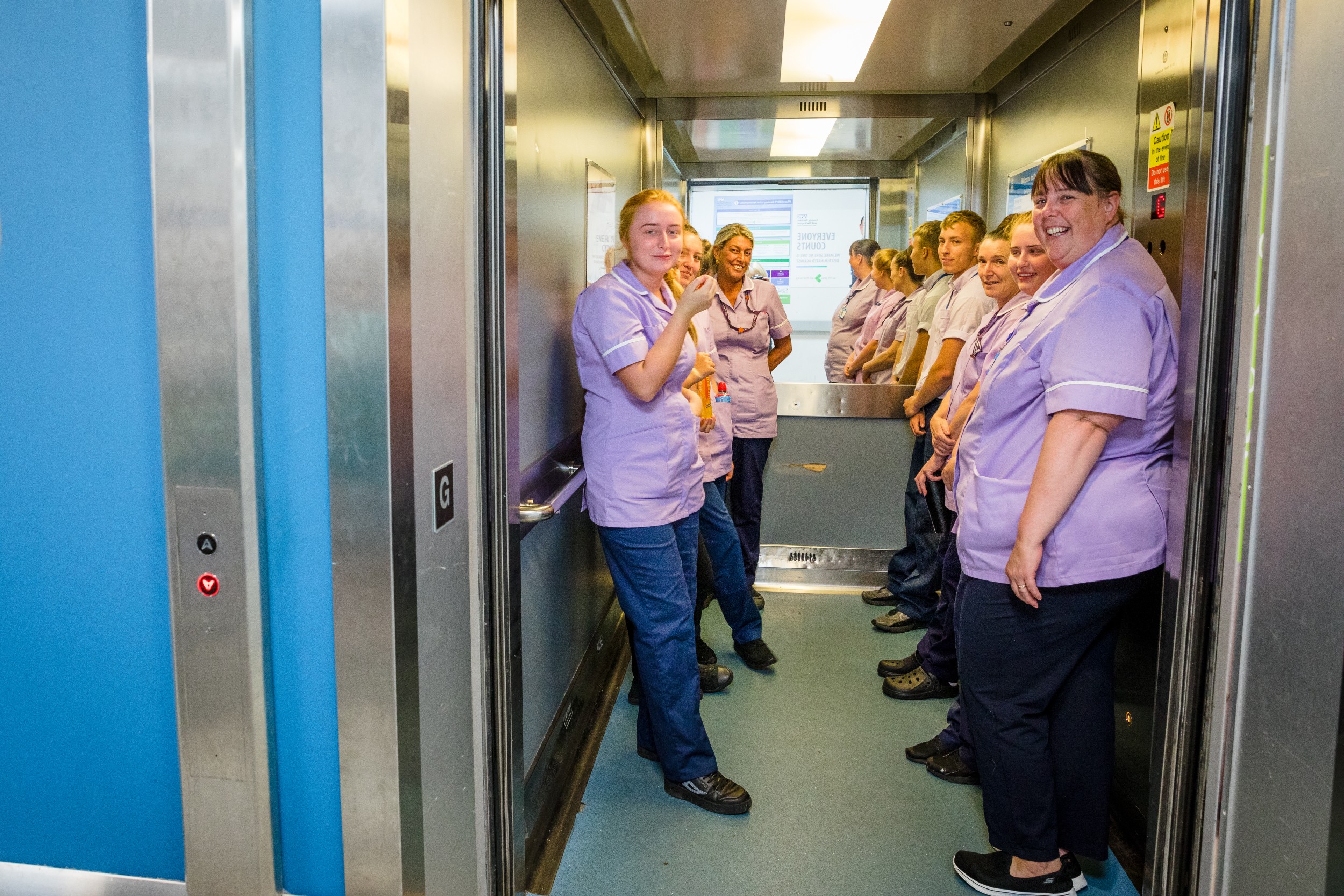 women in purple in a hospital lift smiling