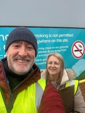 Two people in high vis smiling outside