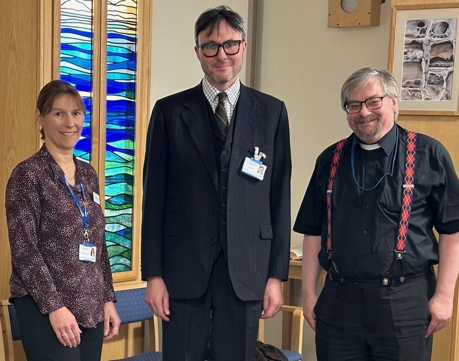 Man in suit with two chaplains in the chapel smiling