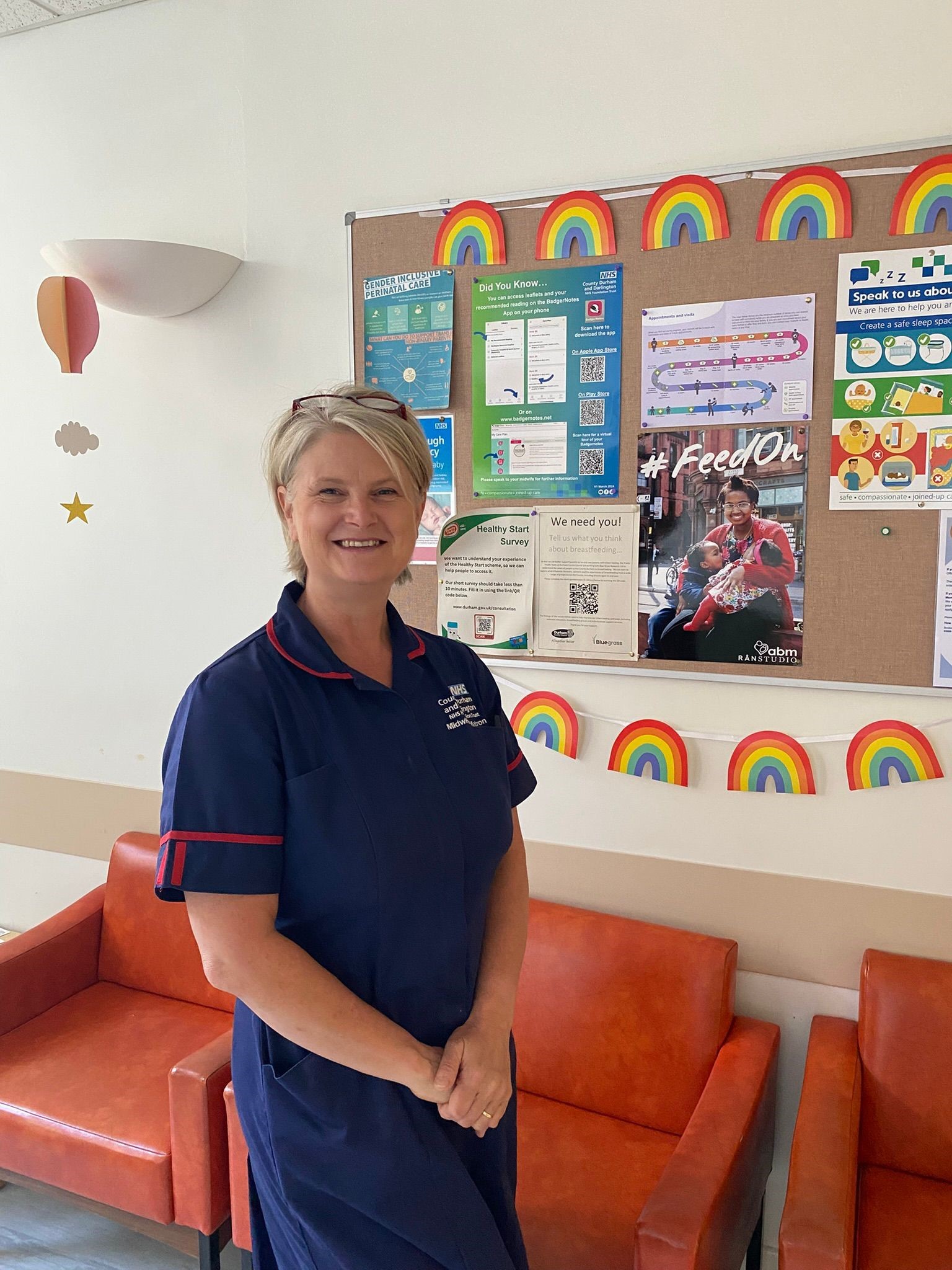 Blonde midwife in uniform smiling on a ward