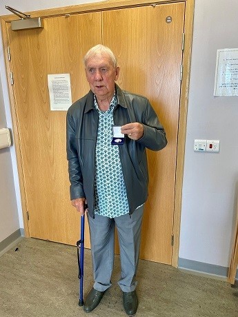 Man with walking stick holding a medal