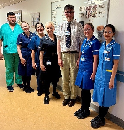 Tall man with smaller women in uniform on a hospital ward