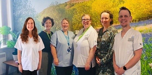 Clinicians in scrubs smiling on a ward