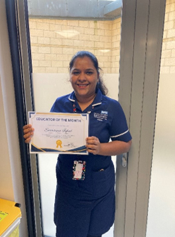 Woman in blue nurses dress holding up a white certifictae
