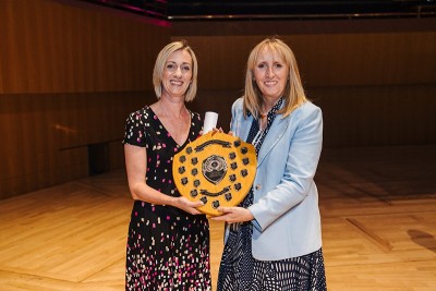 Two women smiling holding a trophy