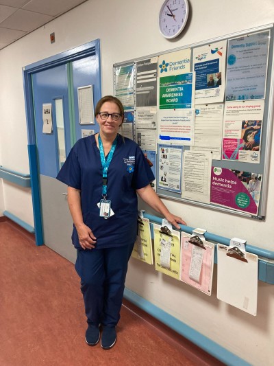 Staff member standing in front of information display board smiling