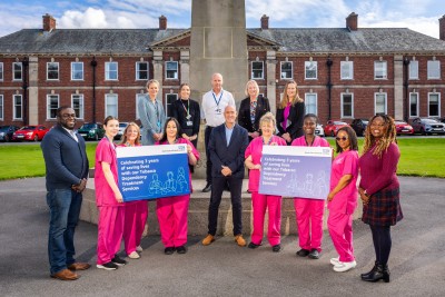 People in uniform and smart clothing smiling outside a hospital
