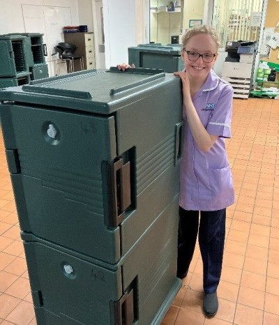 Woman in purple smiling pushing green cart