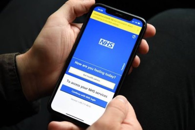 Person holding mobile phone displaying the NHS App on screen