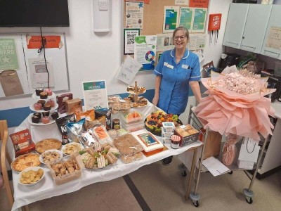 Woman in scrubs standing next to a table full of food