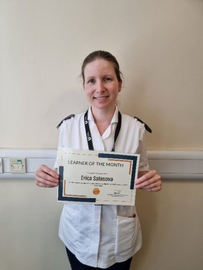 Woman in white uniform smiling holding a certificate