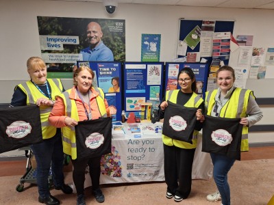 People standing at a stand holding bags