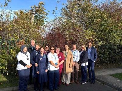 People stood in mixture of uniform and normal clothing outside smiling