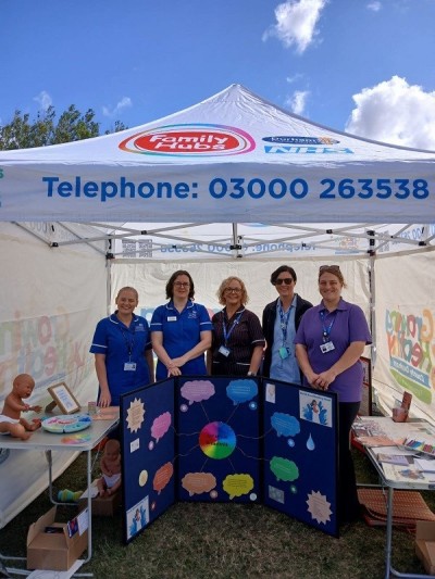 Infant feeding team at a stall outside in uniform smiling