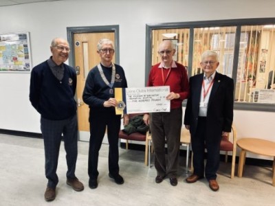 People smiling holding a cheque in a hospital
