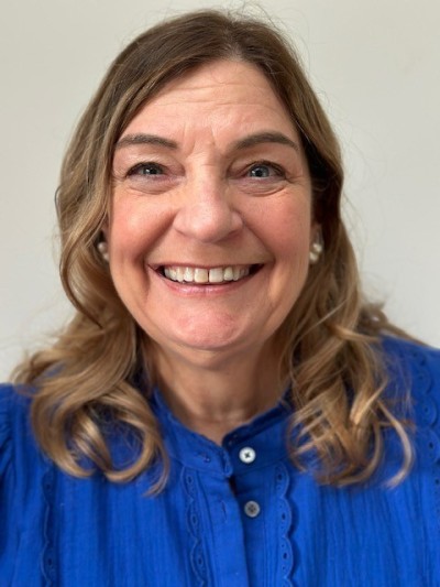 Woman with brown hair smiling in blue top