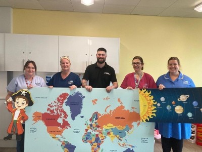 People holding up large artwork on a ward smiling