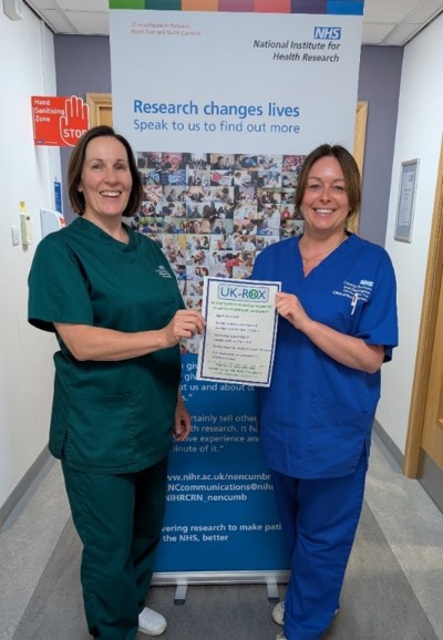 Two nurses smiling holding paper up