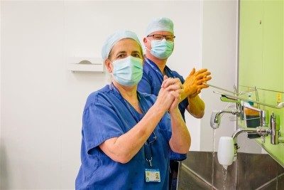 Two staff in scrubs and mask washing hands