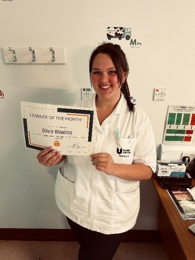 Woman in white uniform smiling holding a certificate