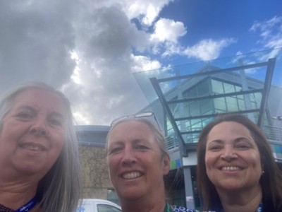 Three women smiling outside of a hospital