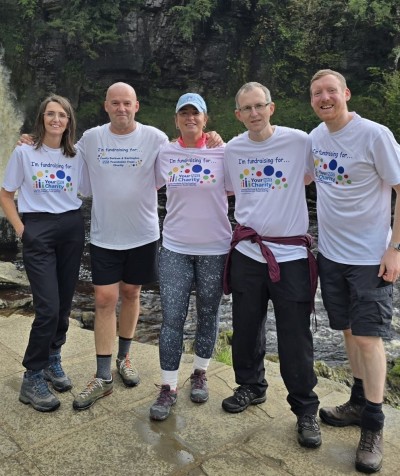 Team wearing white tshirts smiling outside ready to walk