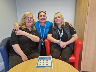 Three women smiling on a sofa