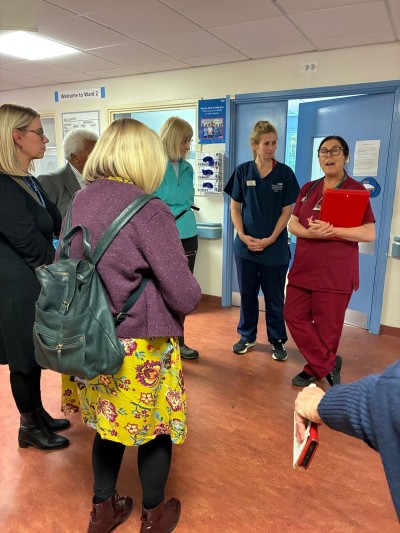 people standing on a ward hearing from doctors and nurses in uniform