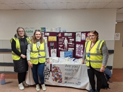 Women in high vis smiling next to a table